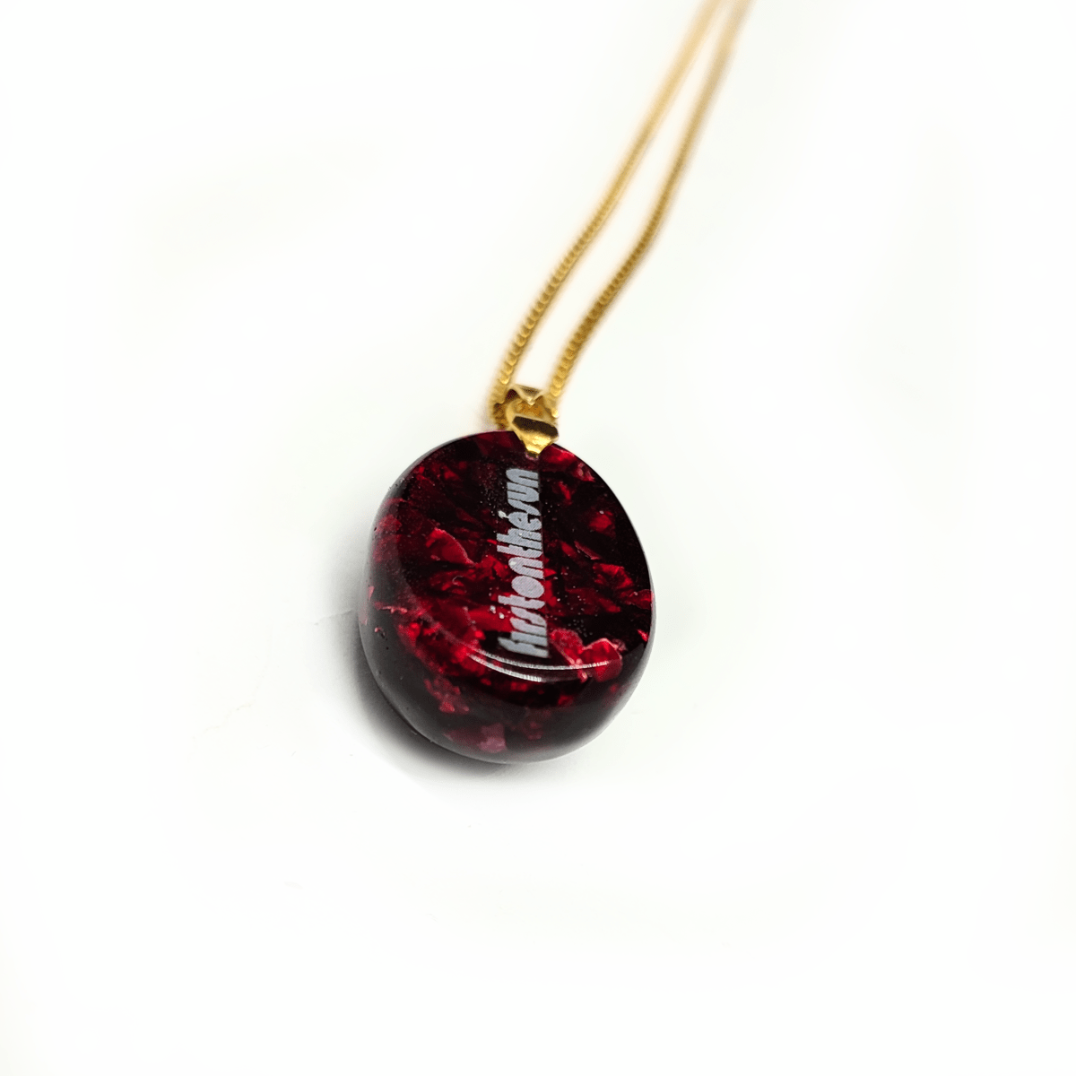 Rückseite eines roten Orgonit Amuletts mit Rubin. Der Orgonit Anhänger ist an einer goldenen Kette befestigt.