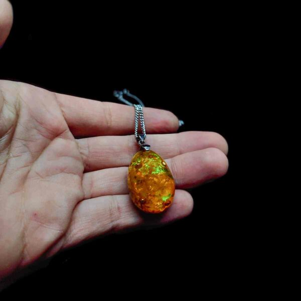Orgonit Amulett aus Citrin & gelbem Opal. Der Anhänger schimmert grünlich & ist an einer silbernen Kette befestigt.