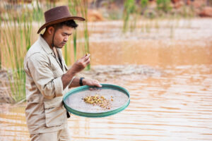Goldwäscher am Fluss mit einer Goldgräberpfanne.