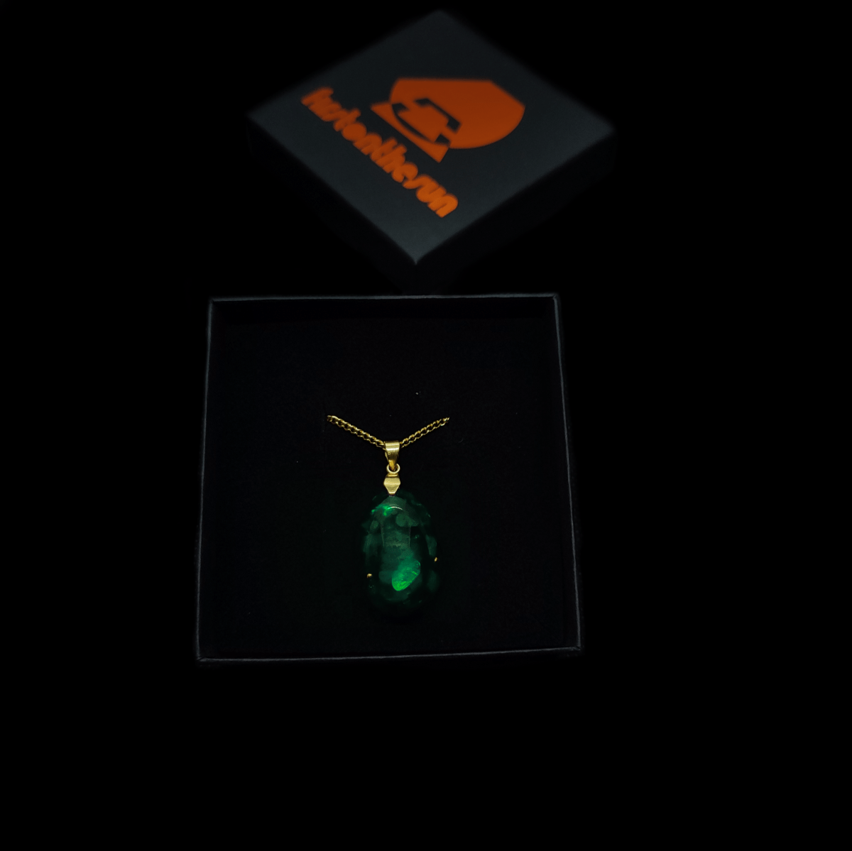 Orgonit Amulett mit Smaragd & firstonthesun Karton. Die Kette des Orgoniten ist vergoldet.