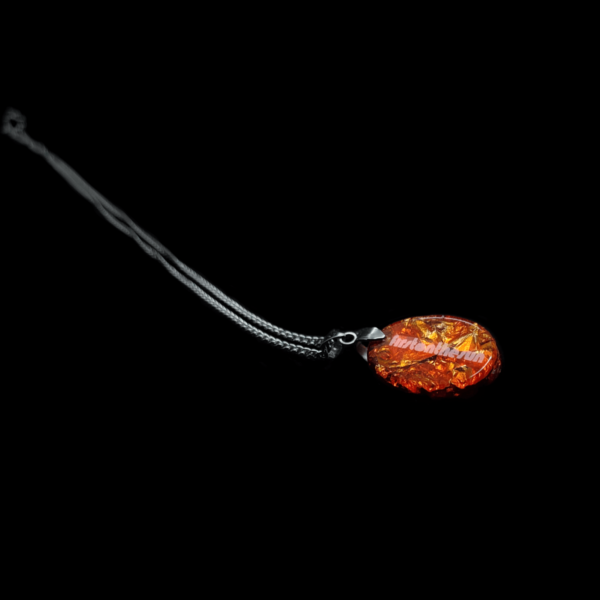 Rückseite eines orangenen Orgonit Amuletts mit silberfarbener Kette.