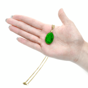 Grünes Orgonit Amulett aus grünen Edelsteinen mit vergoldeter Kette. Dieses Schmuckstück wird von einer Hand gehalten.