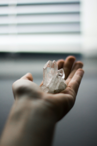 Bergkristall Stein welcher von einer Frauenhand gehalten wird. Der Kristall ist transparent.