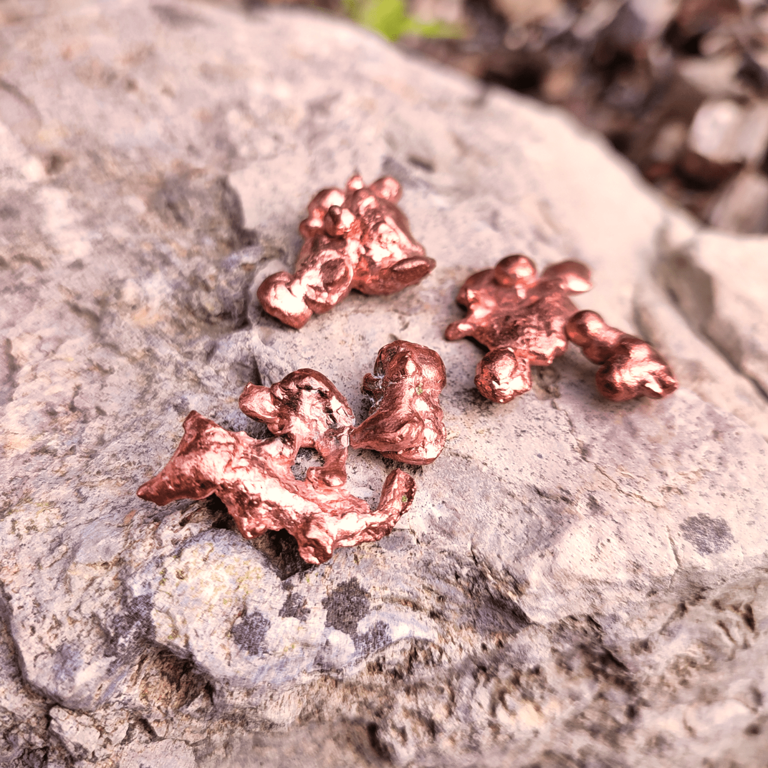 Formschöne Kupfer Nuggets auf Naturhintergrund.