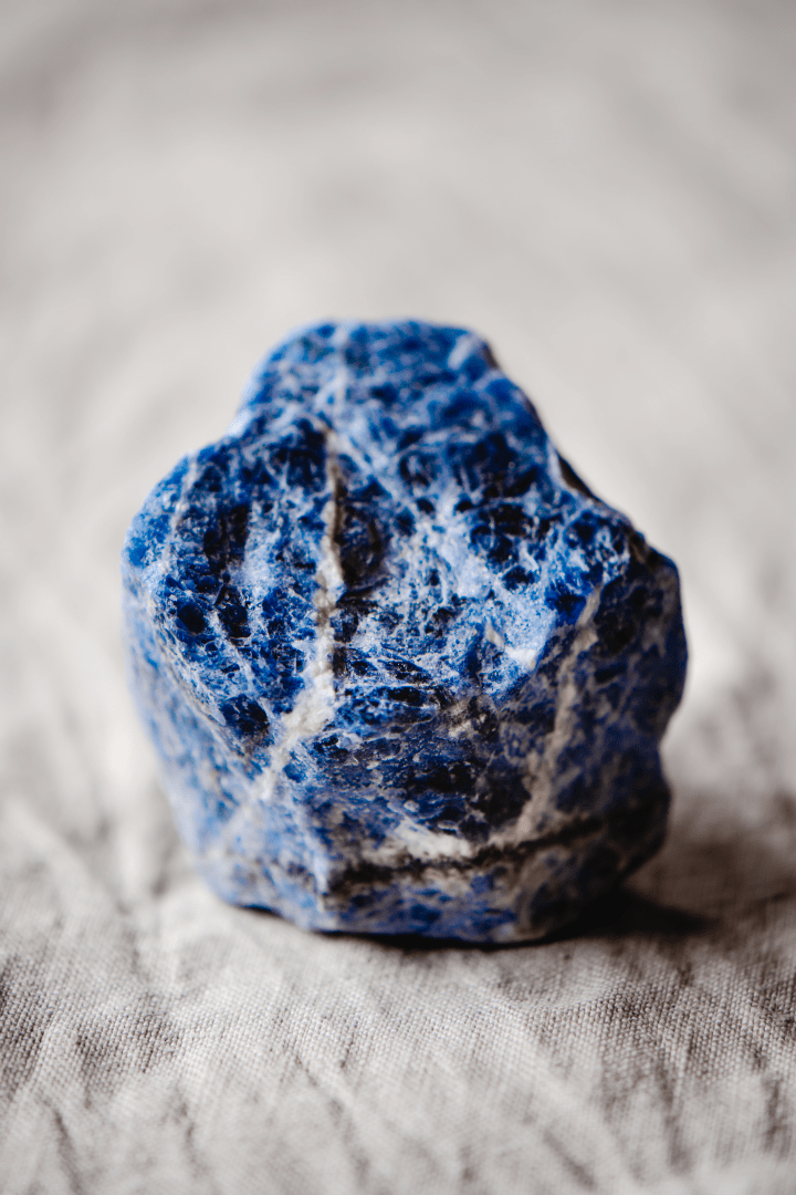 Ein Sodalith Edelstein. Dieses blaue Mineral ist von weißen Linien durchzogen.
