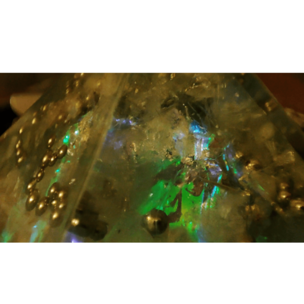 Orgonit Pyramide Polarlicht von nahem. Zu erkennen sind Kristallstrukturen mit Metall Perlen und grünes, blaues & violettes Leuchten.