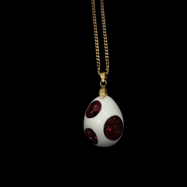 Rot Weißer Orgonit Talisman "Blut des Berges" in Ei Form. Das abgebildete Dino Ei hat rote Punkte & eine goldene Kette.