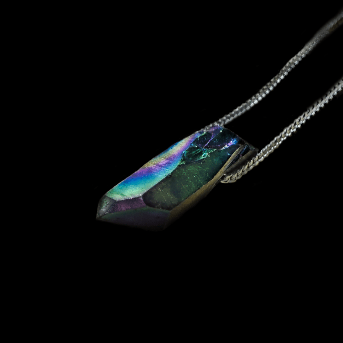 Angel Aura Spitzenanhänger Makro Aufnahme an einer 925 Silber Kette. Angel Aura Kristalle sind mit Eisen beschichtete Kristalle, welche wie auf diesem Foto in Regenbogenfarben erstrahlen.