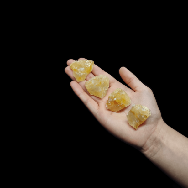 Produktpräsentation von Citrin Rohsteine welche auf der Handfläche einer Frau liegen. Citrin ist gelber Quarz.