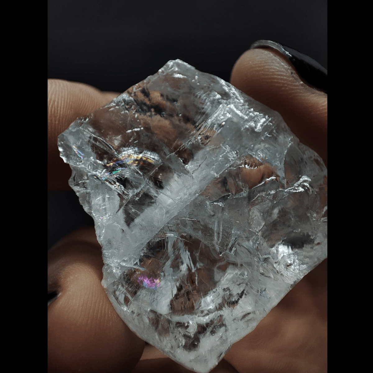 Makroaufnahme eines Bergkristall Rohsteins. Zu erkennen ist die für Bergkristall übliche transparente Kristallstruktur mit regenbogenfarbenen Einschlüssen.