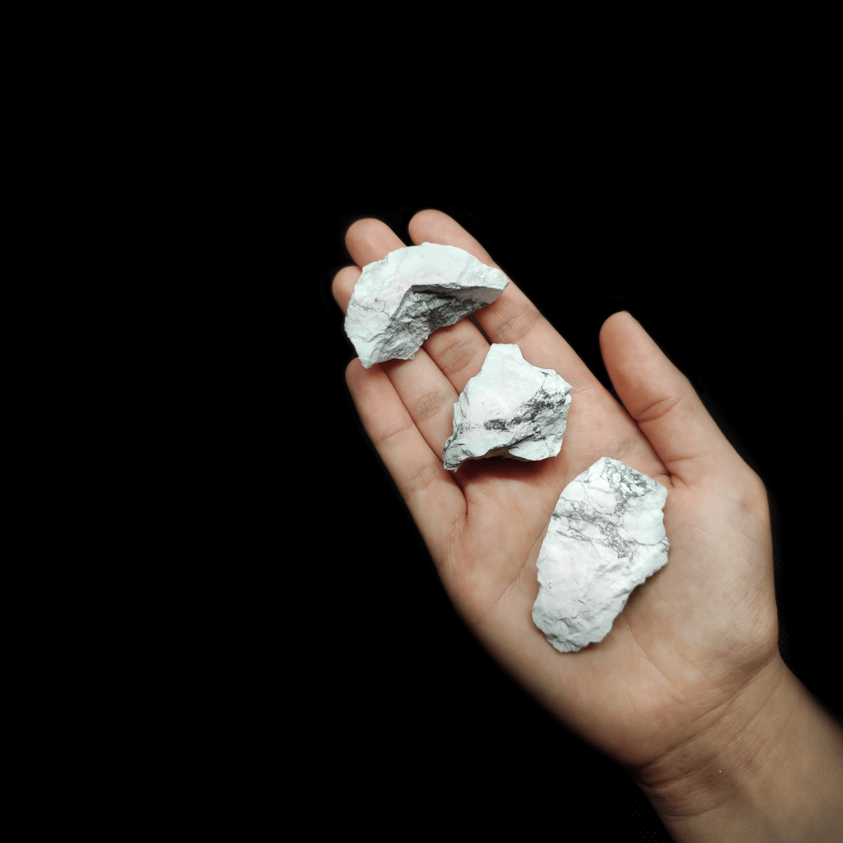 Produktpräsentation natürlicher weißer Magnesit Rohsteine, welchem zum Größen Vergleich auf einer Handfläche liegen.