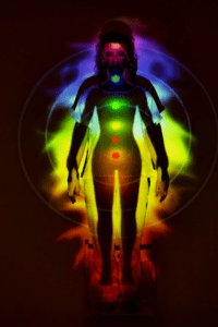 Abbild einer Frau & den 7 Regenbogenfarbenen Chakra Zentren, welche als Lichtpunkte zu sehen sind.