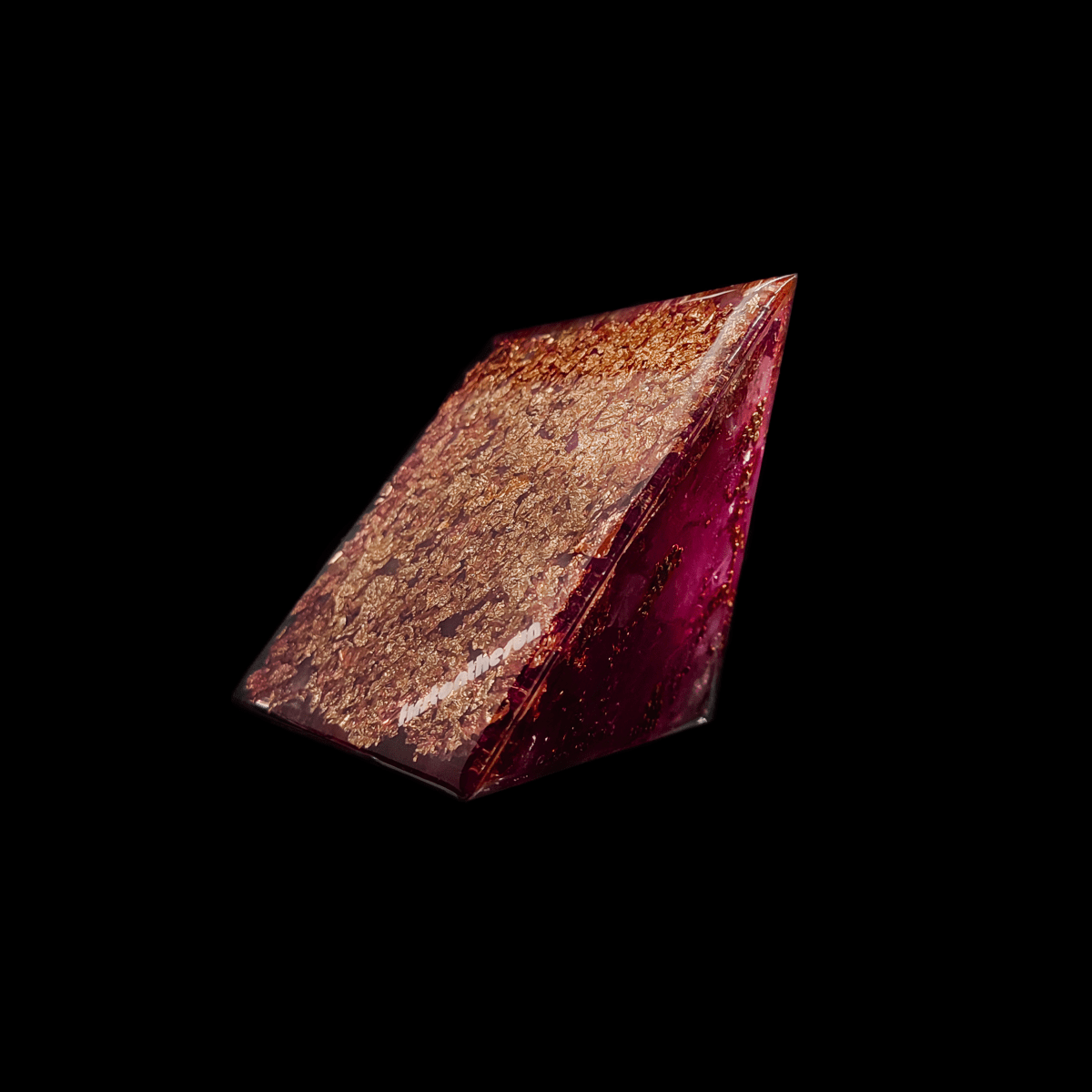 Die mit Blattgold versehene Bodenfläche einer Feenkristall Orgonit Pyramide. Die pinken Edelsteine sind an der Seite gut zu erkennen.