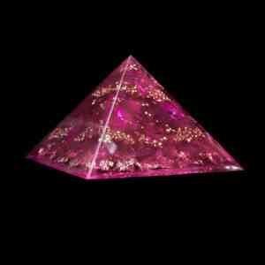 Produktbild der Feenkristall Orgonit Pyramide mit den Edelsteinen pinker Saphir, Herkimer Diamant & Bergkristall. Dieser pinke Orgonit weist zudem goldene Metallelemente auf.