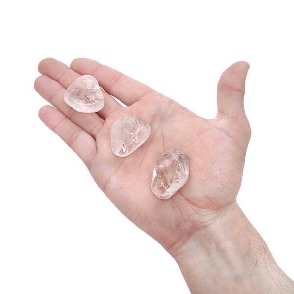 Transparente Bergkristall Trommelsteine welche zur Größenansicht auf einer Hand liegen.