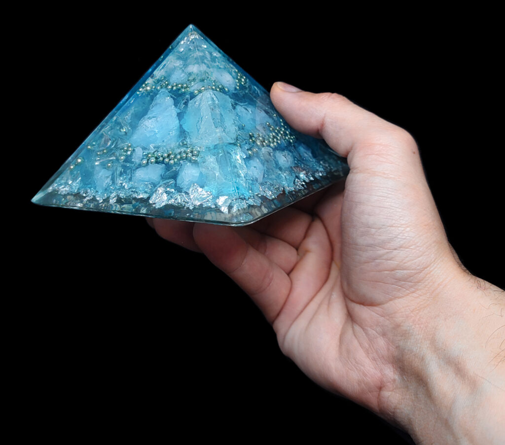 Hellblaue Orgonit Pyramide mit Edelsteinen & Edelmetall, welche man im Shop online kaufen kann.