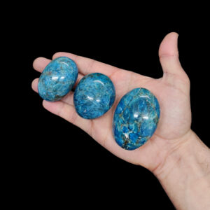 Große runde Apatit Kristalle von blauer Farbe auf einer Handfläche.