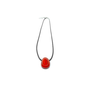 Ein roter Jaspis Kristall in Tropfenform mit Halskette. Das Schmuckband des polierten Edelsteins ist Schwarz.