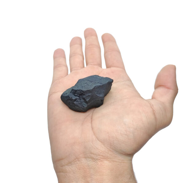 Anthrazit-schwarz farbener Schungit Rohstein zur Produktpräsentation auf einer Hand.